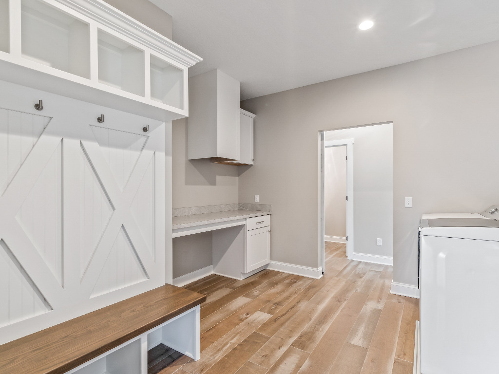 Secondary entryway with coat rack and bench combo, laundry machine, and built in desk nook in Modern Farmhouse Home by PH Design, custom construction home builders in Canton, OH