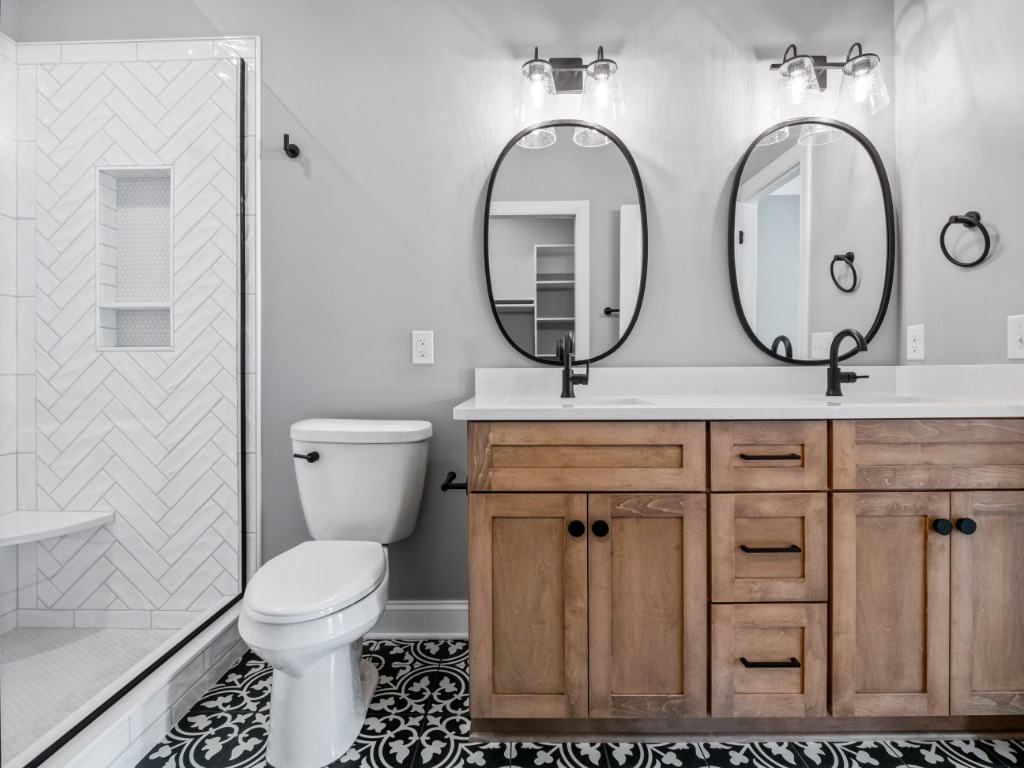 Bathroom in Traditional Farmhouse with herringbone white tile shower, black and white floor tile, and wooden cabinetry by PH Design, custom construction home builders in Canton, OH