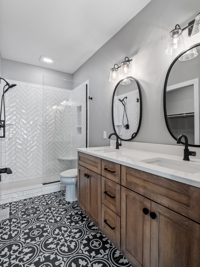 Bathroom in Traditional Farmhouse with herringbone white tile shower, black and white floor tile, and wooden cabinetry by PH Design, custom construction home builders in Canton, OH
