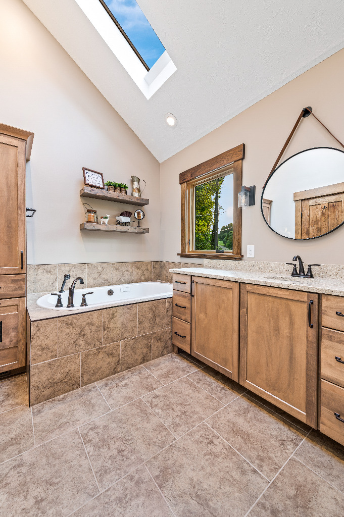 Rustic Bathroom renovation with tiled bathtub, granite vanity top, and wooden cabinetry by PH Design, custom construction and renovation company in Canton, OH