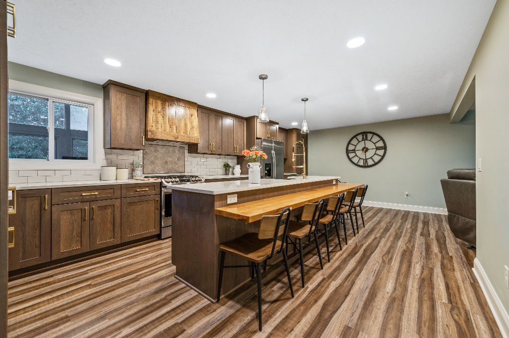 Eclectic Kitchen renovation with kitchen island and bar combo, wooden cabinetry, marble countertops, and hardwood floor by PH Design, custom construction and renovation company in Canton, OH