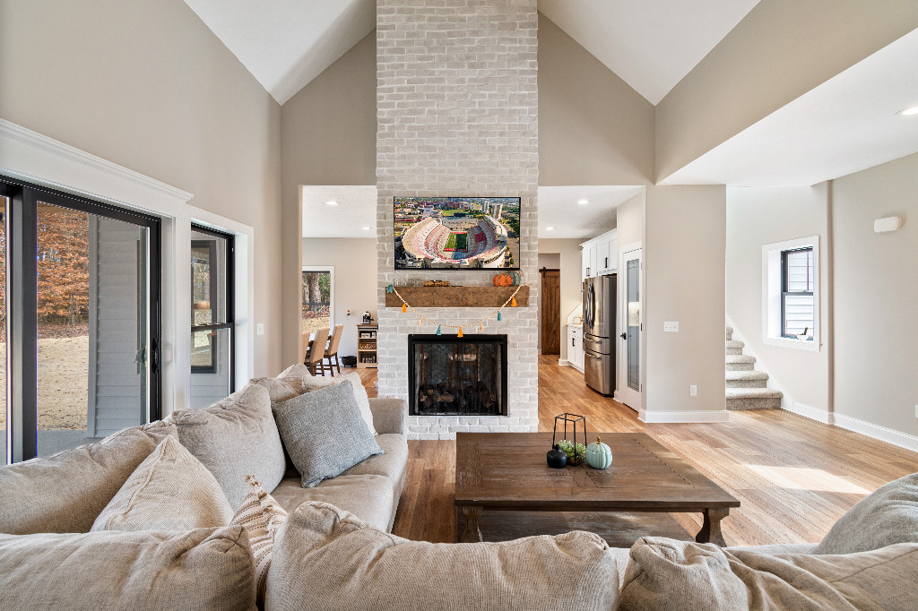 Living room with cathedral ceilings, double-sided brick fireplace, and sliding patio door